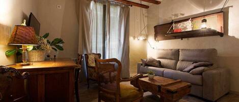 Ein gemütliches Wohnzimmer mit einer Couch, Sesseln, einem Tisch und einer Lampe.