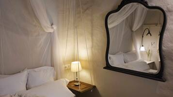 Un dormitorio con cama con dosel, una lámpara de noche y un espejo en la pared.