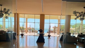 Un hall d’entrée spacieux avec un mur de verre donnant sur la piscine et le paysage désertique.