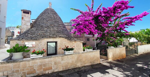 A stone building with a conical roof, a small door, and a sign reading "TRULLI ANTICA FONTE." - Trulli Antica Fonte (Alberobello)