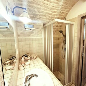 A bathroom with a shower, a sink, and a mirror. - Trulli Antica Fonte (Alberobello)