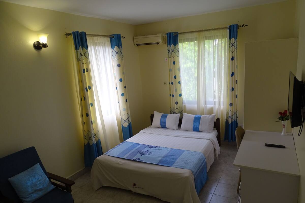A hotel room with a bed, a desk, a chair, and curtains.