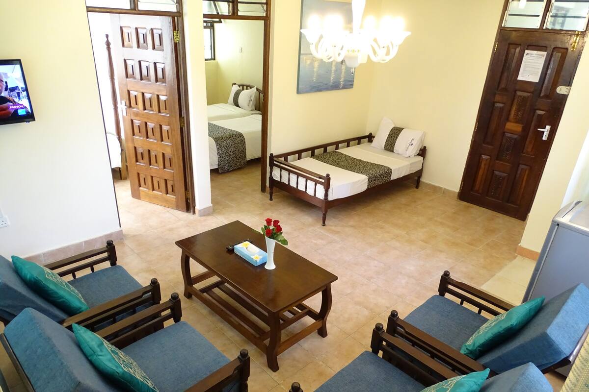 A hotel room with a bed, a sofa, a table, and a TV.