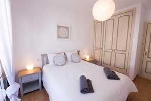 Un lit bien fait, avec des oreillers, une lampe de chevet et une serviette enroulée posée sur le lit.
