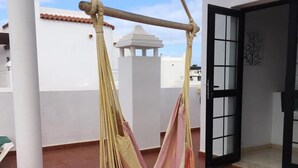 A hammock suspended between two columns on a tiled terrace.