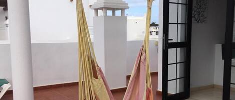 A hammock suspended between two columns on a tiled terrace.