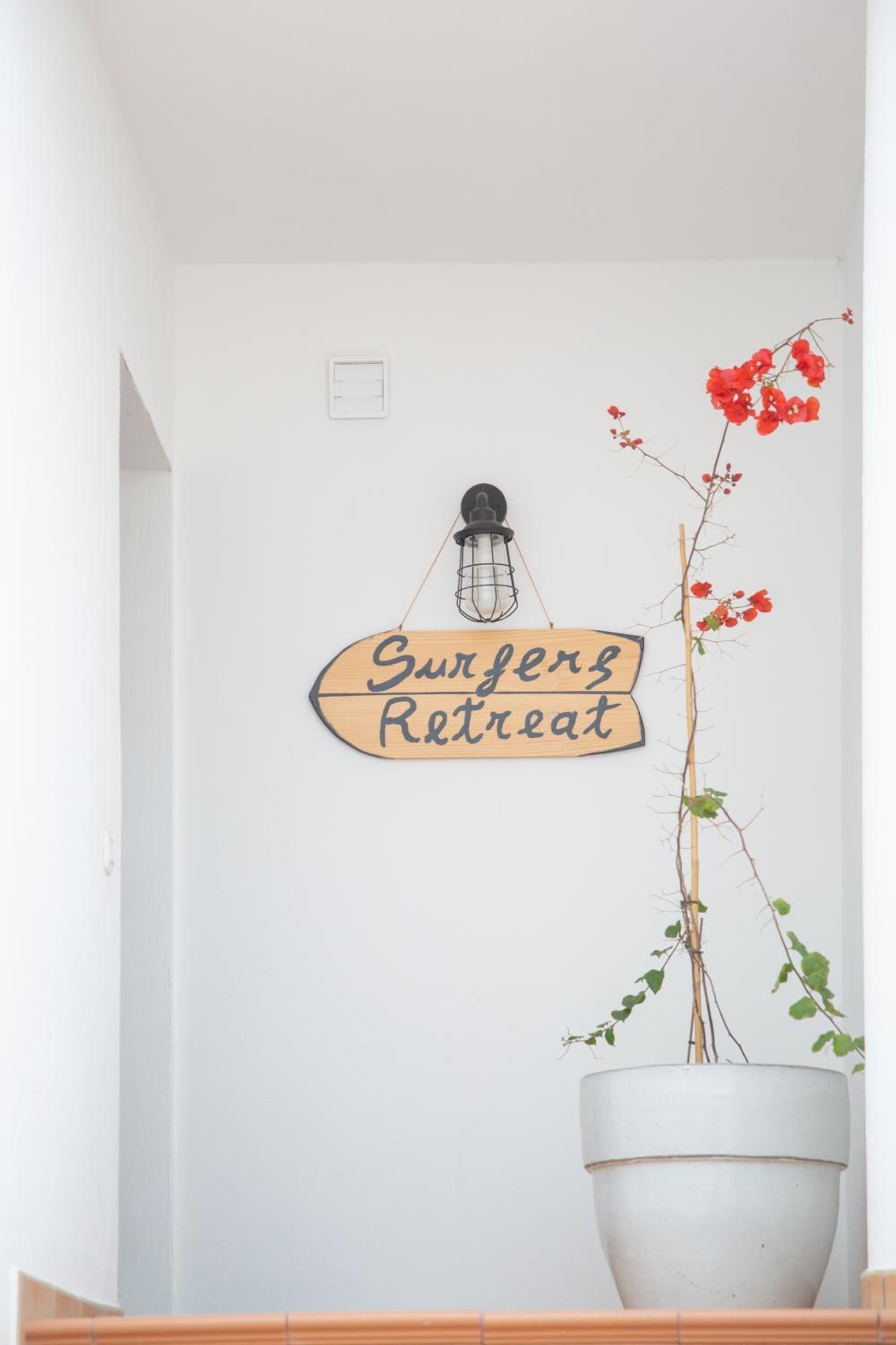A wall with a sign that reads 'Surgery Retreat' and a potted plant with red flowers.