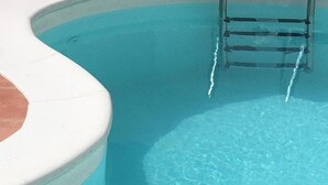 A clear blue pool with a ladder leading into it.