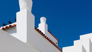 A white building with a red-tiled roof and a chimney.