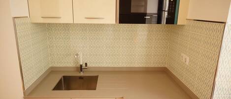 A kitchen with a stainless steel sink, a microwave, and patterned backsplash tiles.