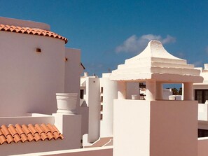 Un bâtiment blanc avec un toit en tuiles et une structure blanche surmontée d’un toit en forme de flèche.