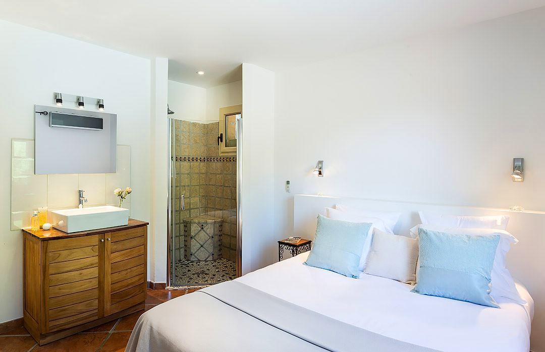 Ein Hotelzimmer mit einem großen Bett, einem Holfach mit einem Waschbecken, einer Duschkabine und einem kleinen Tisch.