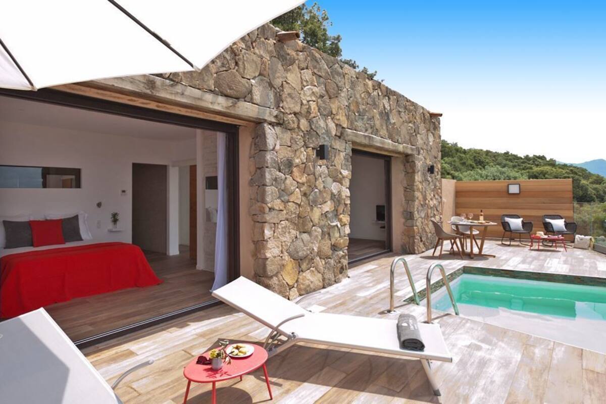 Une villa moderne avec une façade en pierre, une piscine et un espace repas.