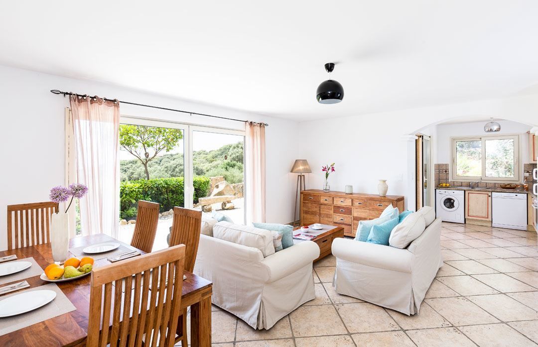 A spacious living area with a dining table, two sofas, and a kitchen in the background.