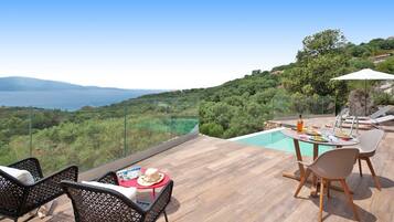 Une terrasse avec piscine, des sièges extérieurs et une vue panoramique sur le paysage.