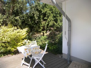 A patio with a table and chairs, surrounded by greenery and trees. - Vacation apartment 5 Wiedehopf - Holiday home 1A - 15 minutes by bike to the (Heringsdorf)