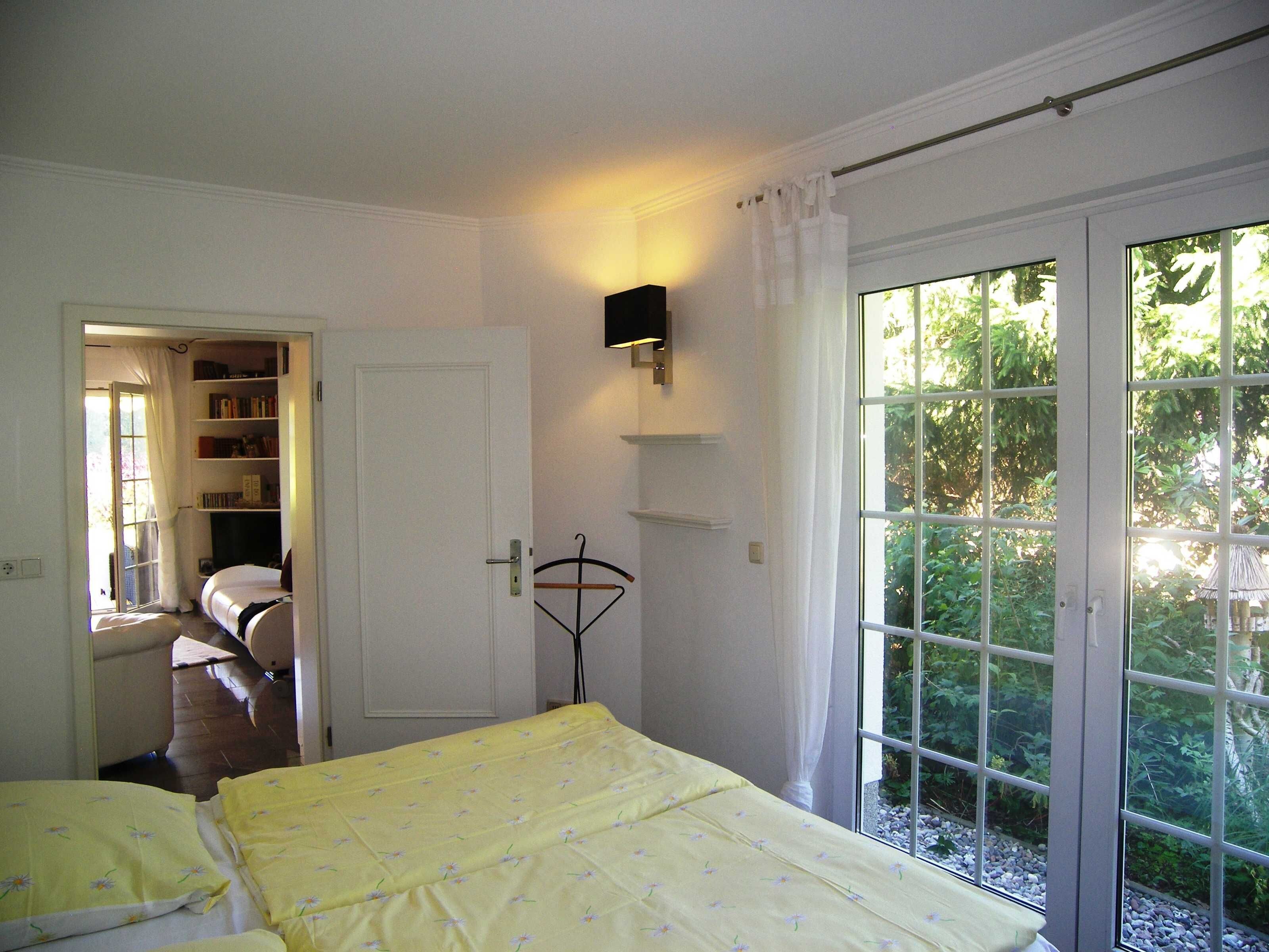 Une chambre à coucher avec un lit, une bibliothèque et une fenêtre donnant sur un paysage verdoyant.