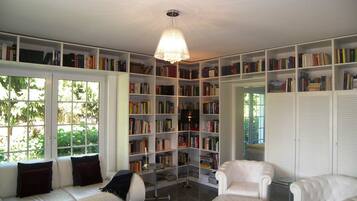 Eine Bibliothek mit weißen Regalen voller Bücher, einem weißen Sofa und einem weißen Sessel.