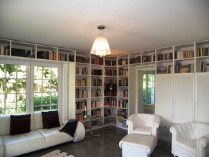 A library with white shelves filled with books, a white sofa, and a white armchair.