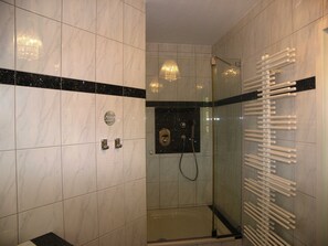 A modern bathroom with marble tiles, a glass shower enclosure, and a towel rack. - Vacation apartment 5 Wiedehopf - Holiday home 1A - 15 minutes by bike to the (Heringsdorf)