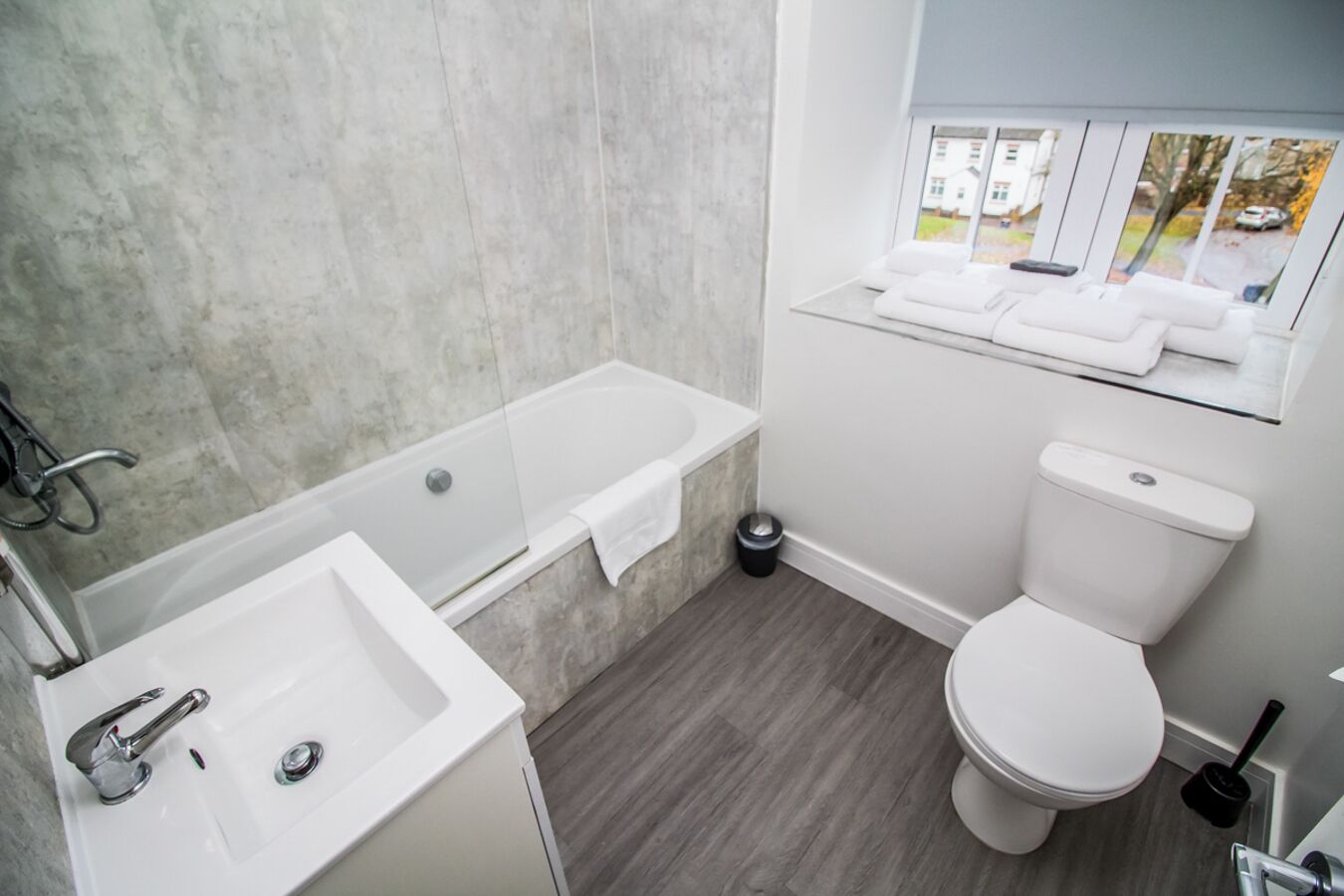 Une salle de bain moderne équipée d’une baignoire, d’un lavabo, de toilettes et d’une fenêtre donnant sur l’extérieur.