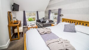 A bedroom with a bed, a desk, a chair, a television, and a window with curtains. - The Saxon Inn (Bishop Auckland)