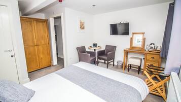 Una habitación de hotel con cama, escritorio con silla, televisor y armario.