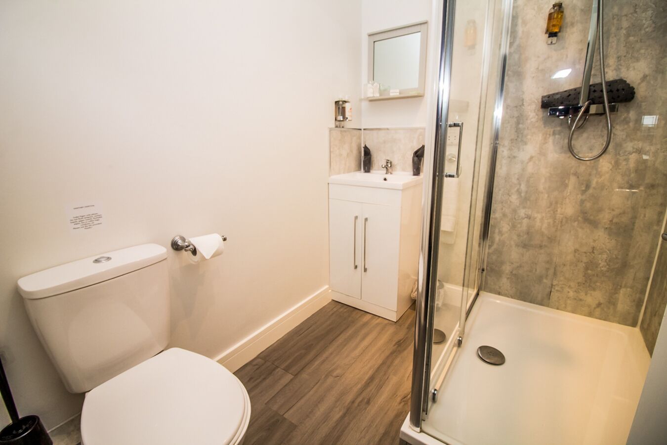 A bathroom with a toilet, a sink, a shower, and a cabinet.