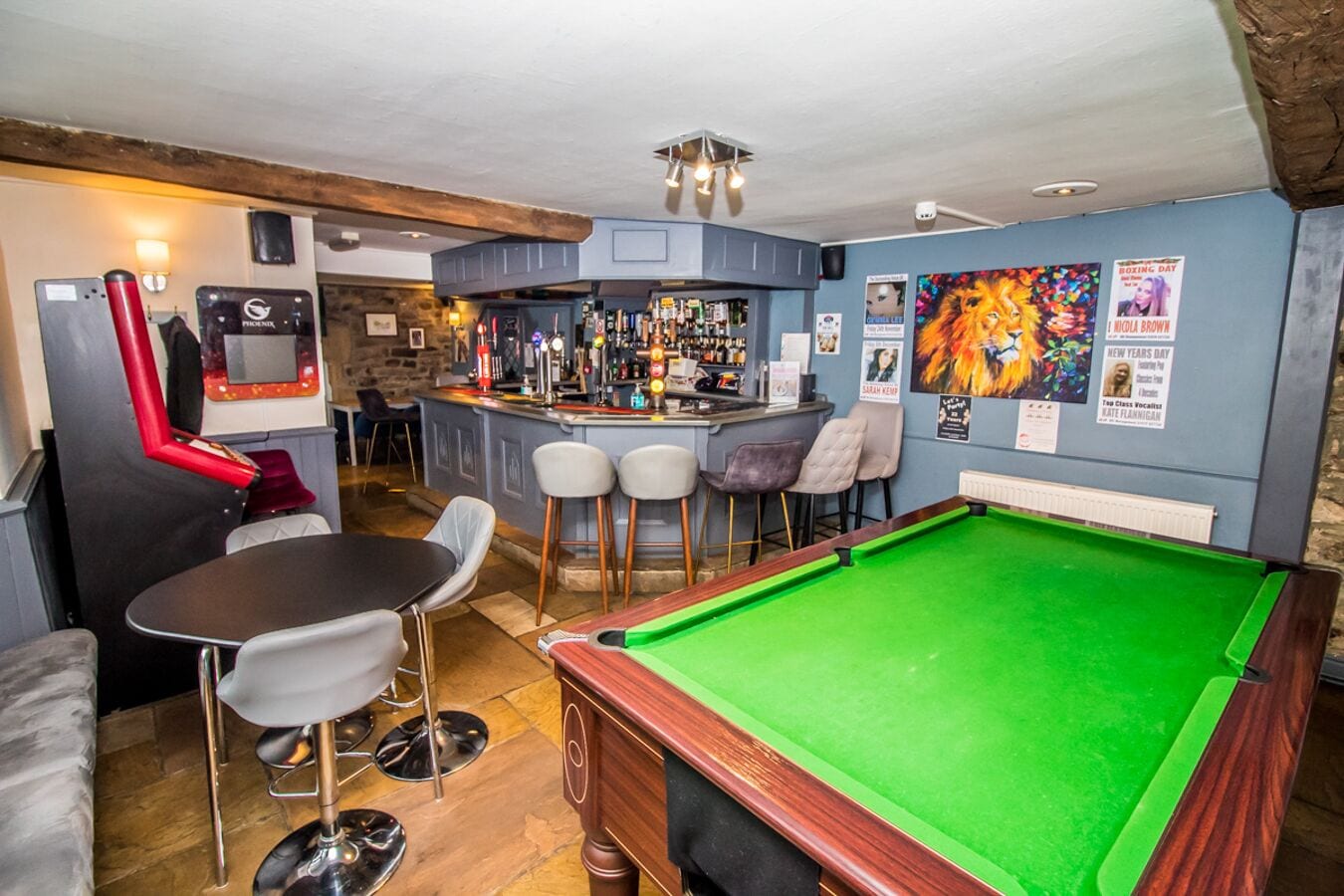 A bar area with a pool table, bar stools, and a pool table with a green felt surface.
