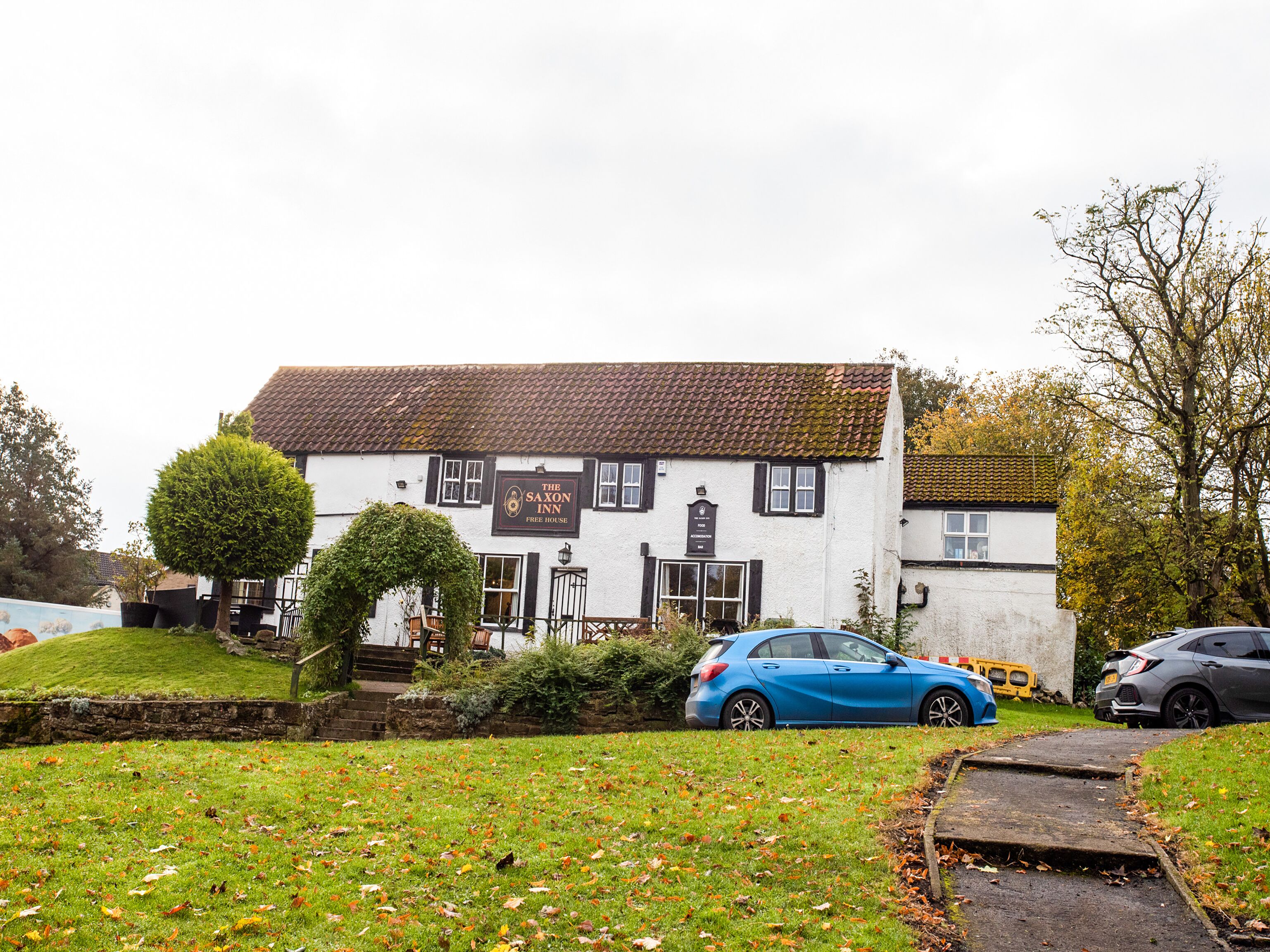 Un edificio blanco tradicional con un letrero que dice 'The Saxon Inn Free House'.