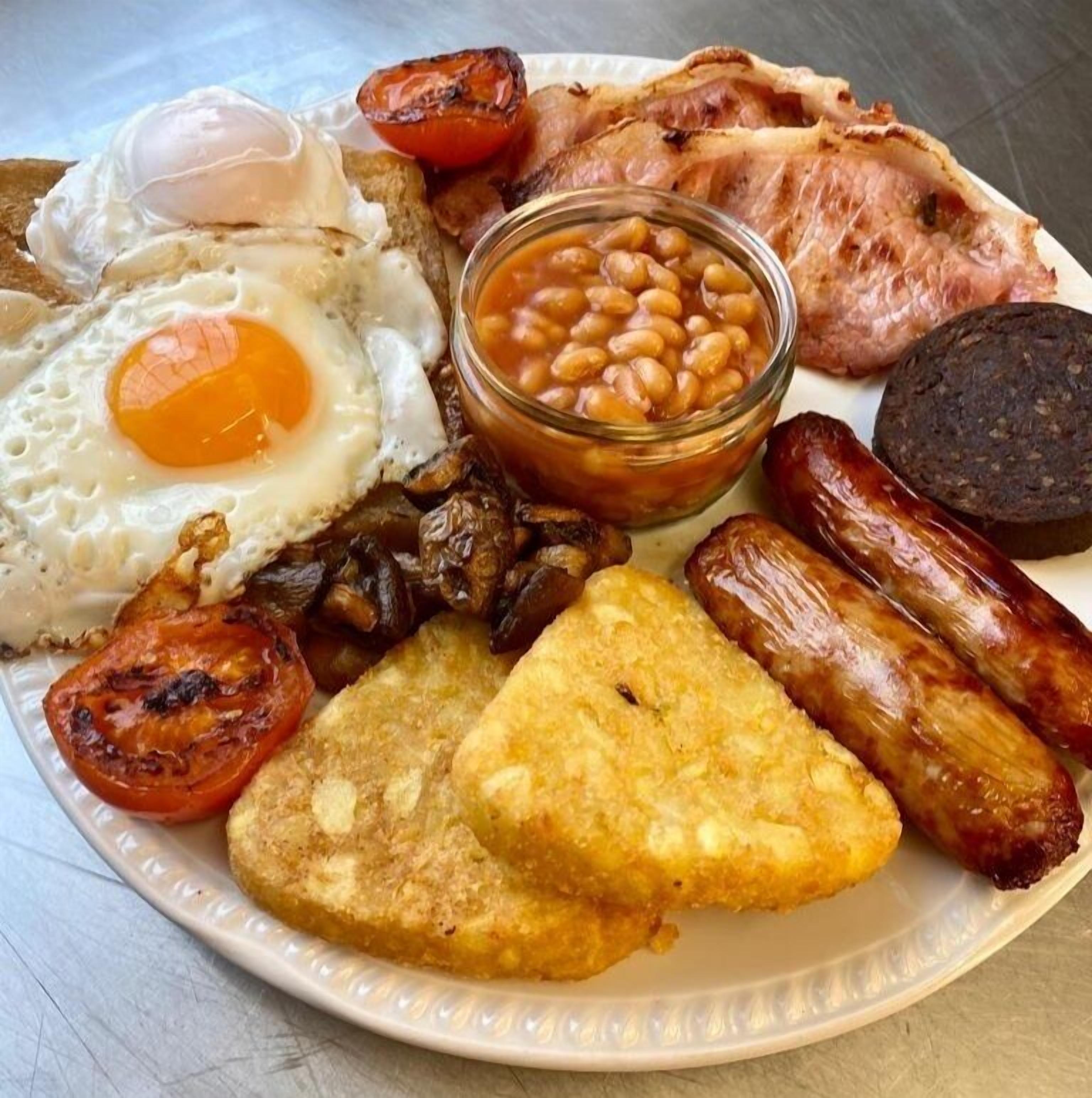 A plate of breakfast foods including eggs, sausages, tomatoes, beans, and toast.