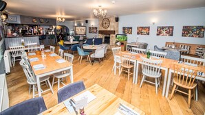 A restaurant with multiple dining areas, including a bar and a seating area with a fireplace. - The Saxon Inn (Bishop Auckland)