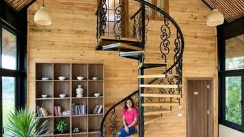 A spiral staircase with a wooden finish and black metal railings, leading to a second floor.