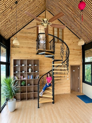 Una escalera de caracol con detalles de madera y barandillas de metal negro, que conduce a un segundo piso.