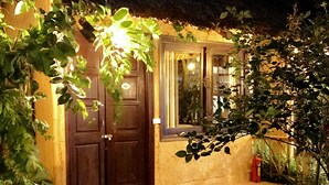 A house with a dark wooden door, a window with curtains, and a small porch area.
