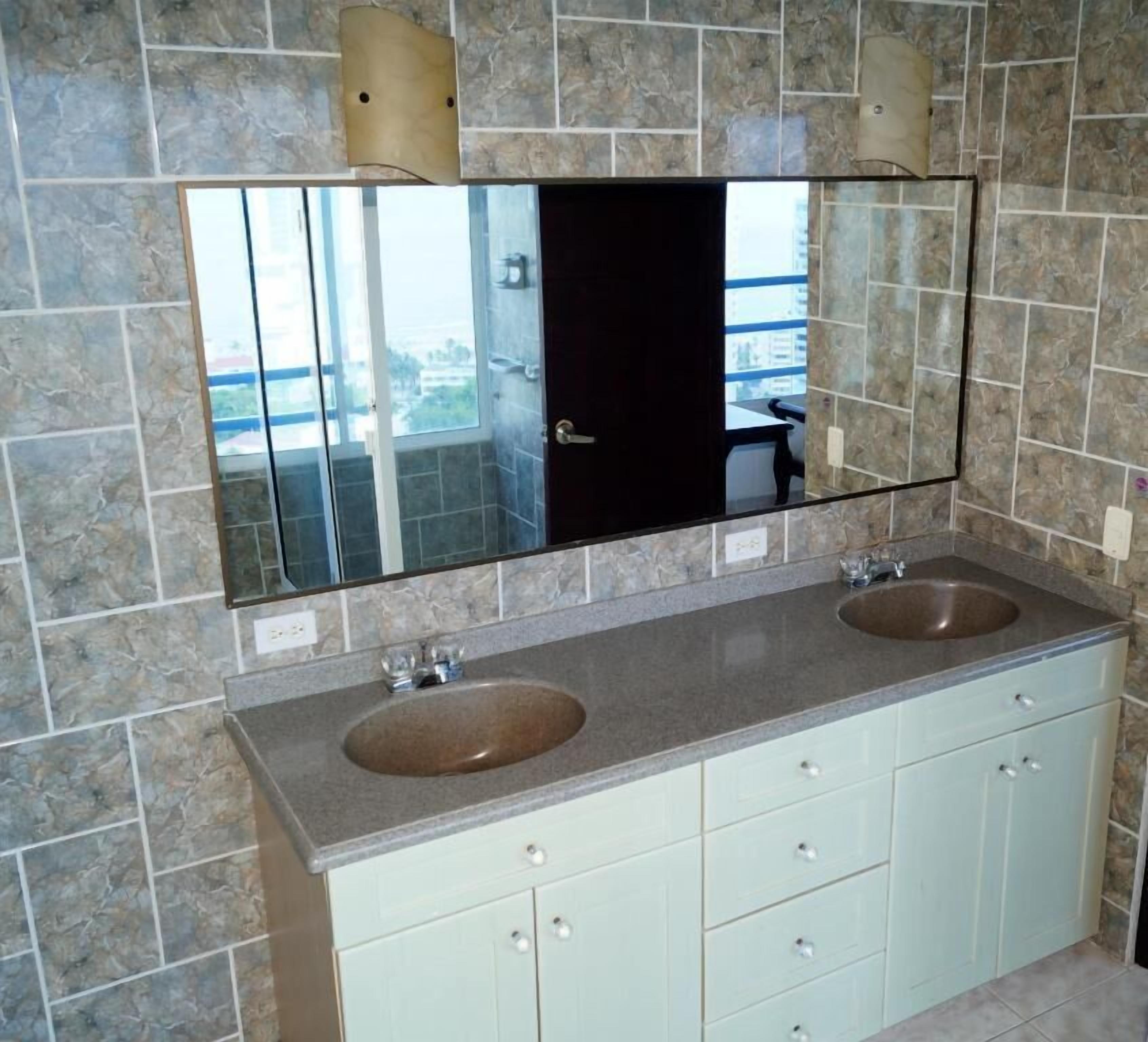 Ein Badezimmer mit zwei Waschbecken, einem großen Spiegel und hellen Schränken.