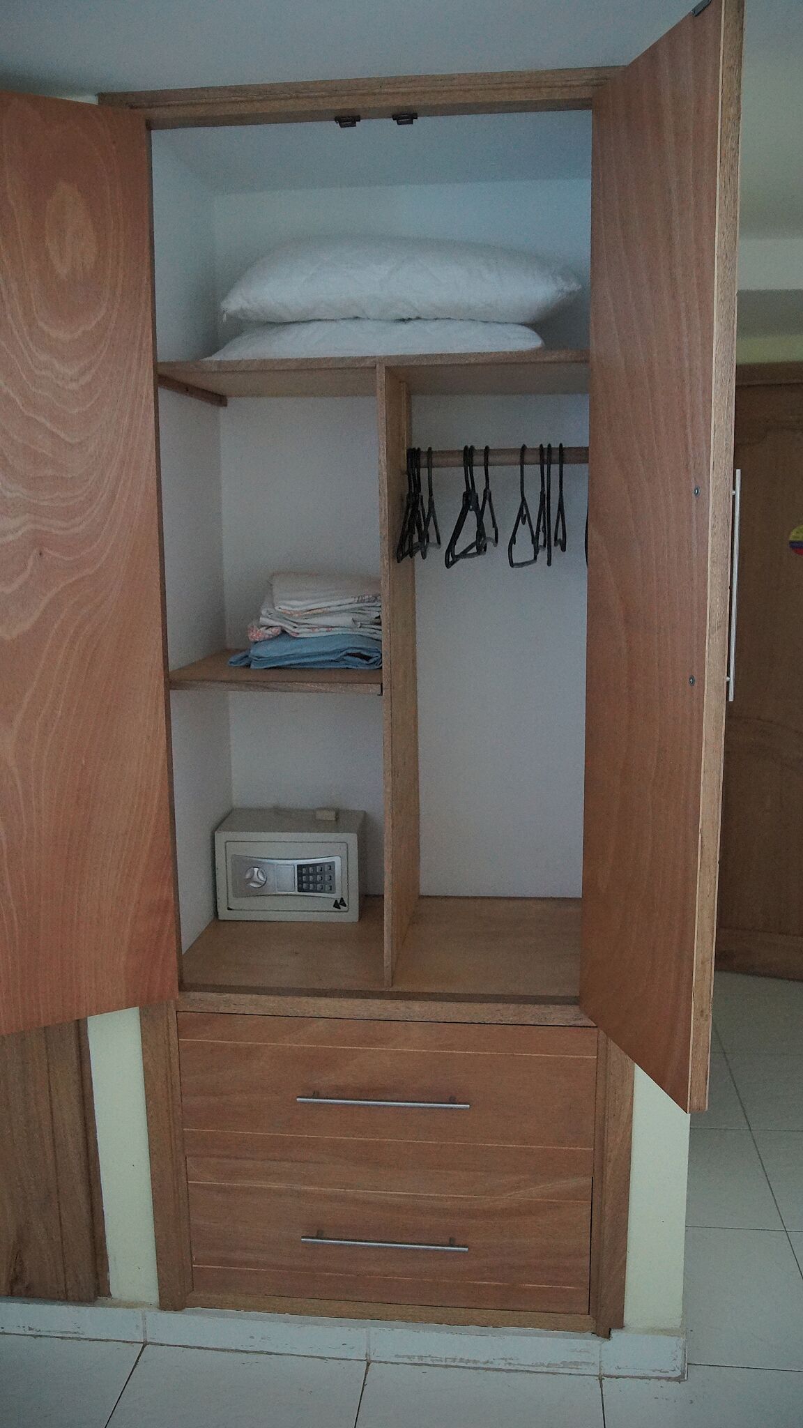 Ein Holzkleiderschrank mit mehreren Regalen, einer Kleiderstange und einem kleinen Gerät.