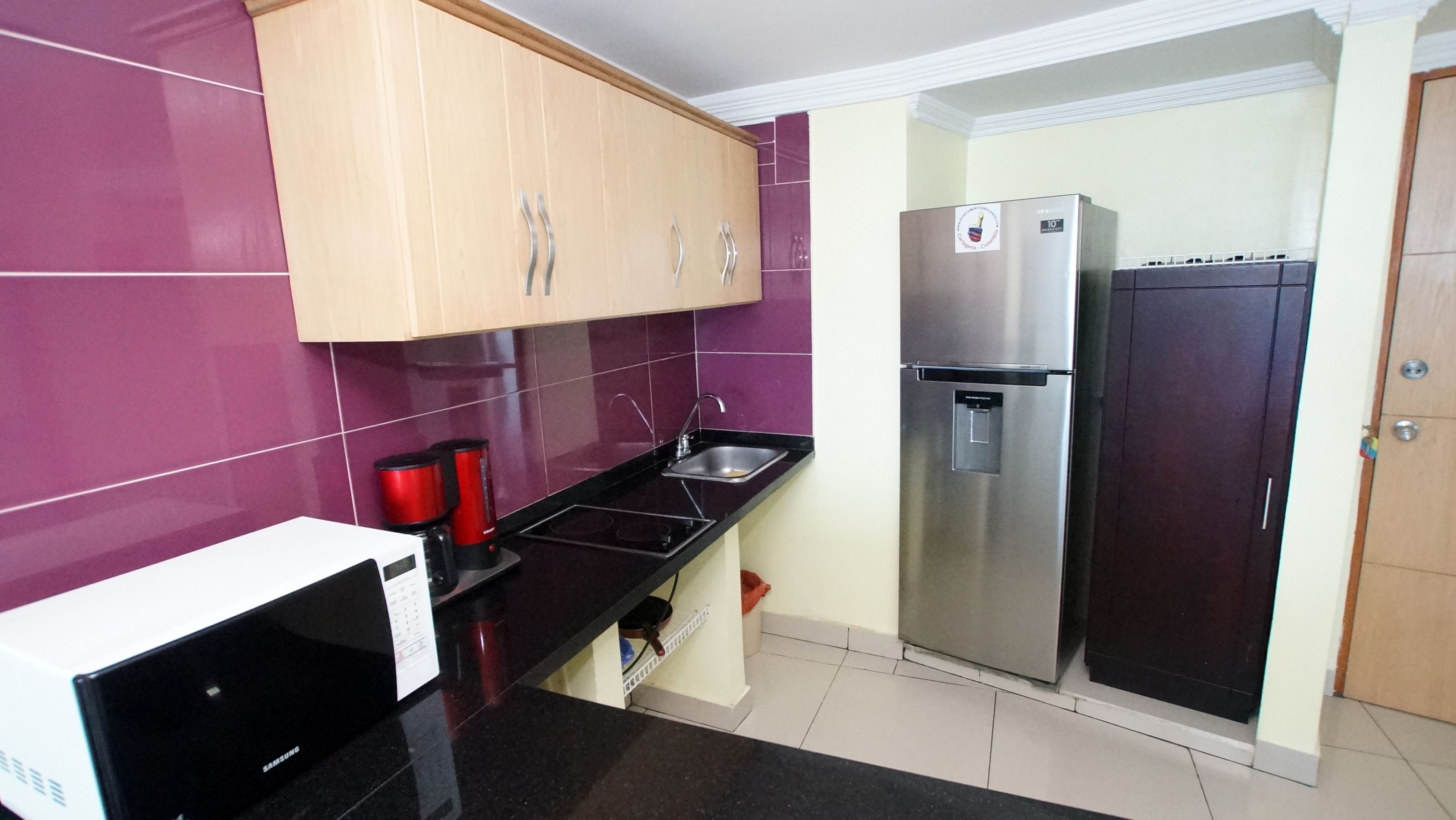 A compact kitchen with a microwave, a coffee maker, a sink, and two refrigerators.