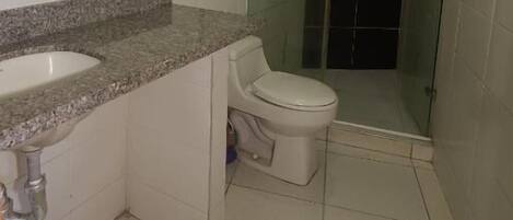 Une salle de bain avec un lavabo sur un plan de travail en granit, des toilettes et une cabine de douche en verre.