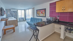 A modern kitchen with a blue sofa, a dining table, and a kitchen island. - Apartamentos Bacanos (Cartagena)