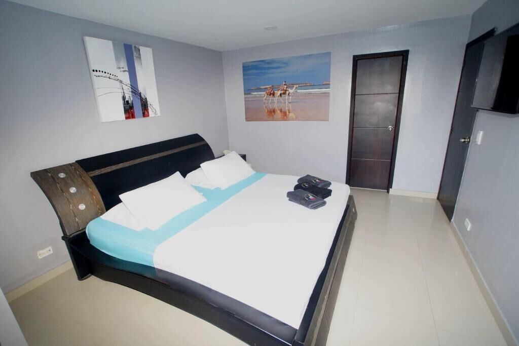 A bedroom with a bed, a door, and two wall-mounted pictures.