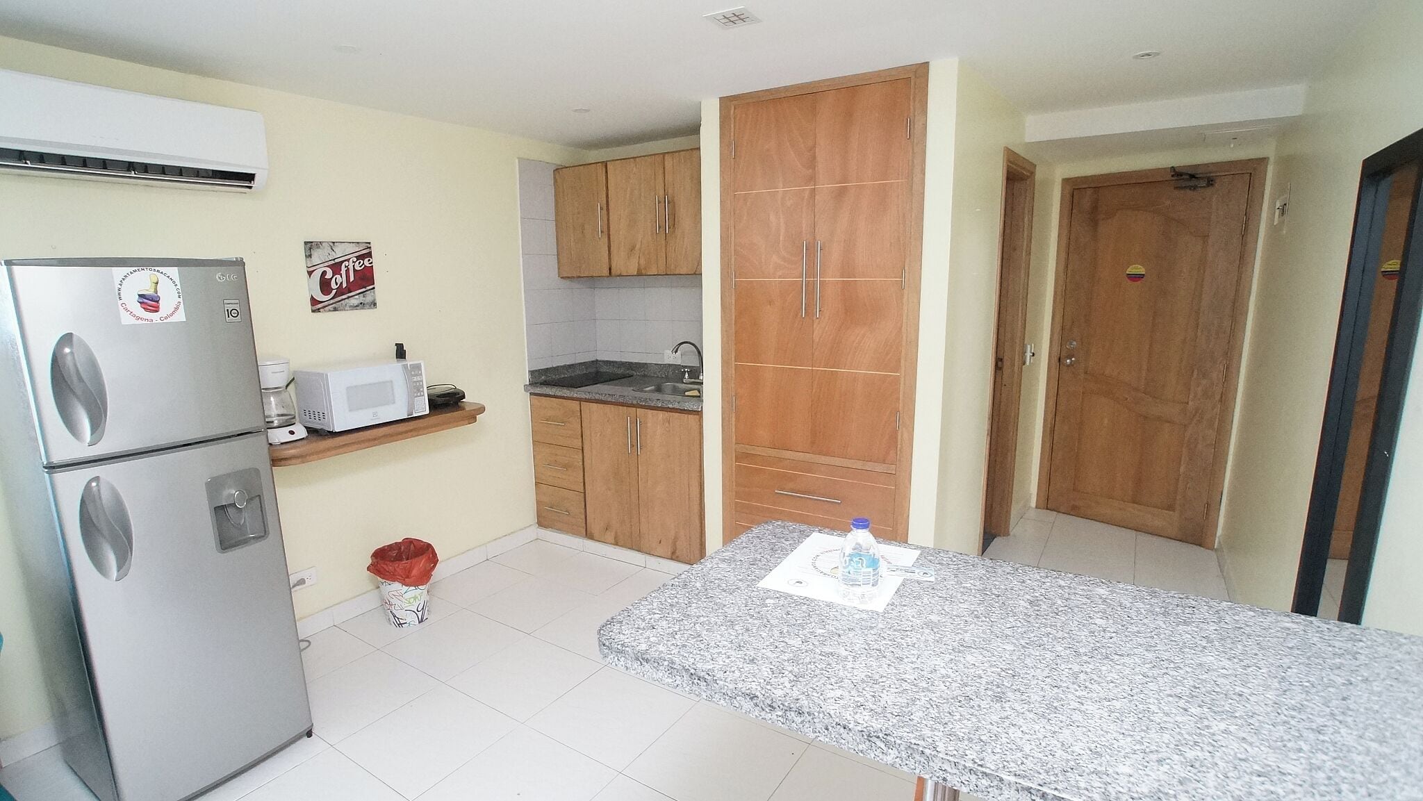A compact kitchen with a refrigerator, microwave, and wooden cabinets.