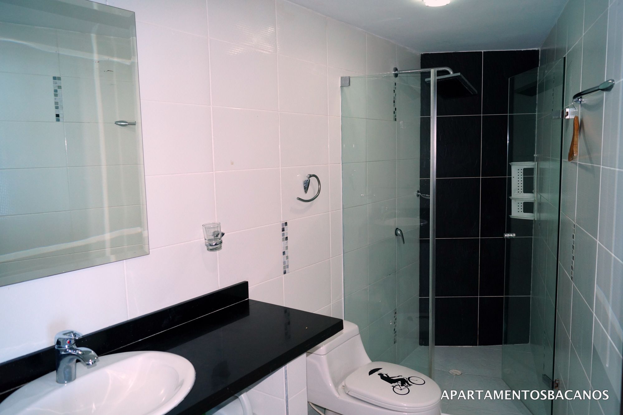 A bathroom with a white sink, black countertop, and a glass shower enclosure.