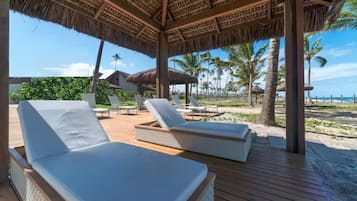 Na praia, areia branca, espreguiçadeiras, guarda-sóis