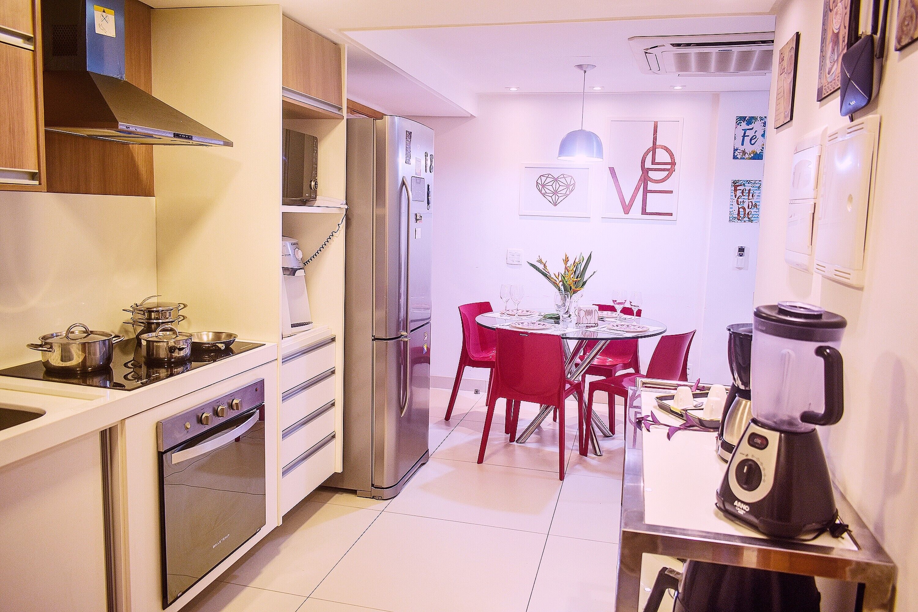 Cocina compacta con estufa, horno y refrigerador. Hay una zona de comedor con mesa y sillas.