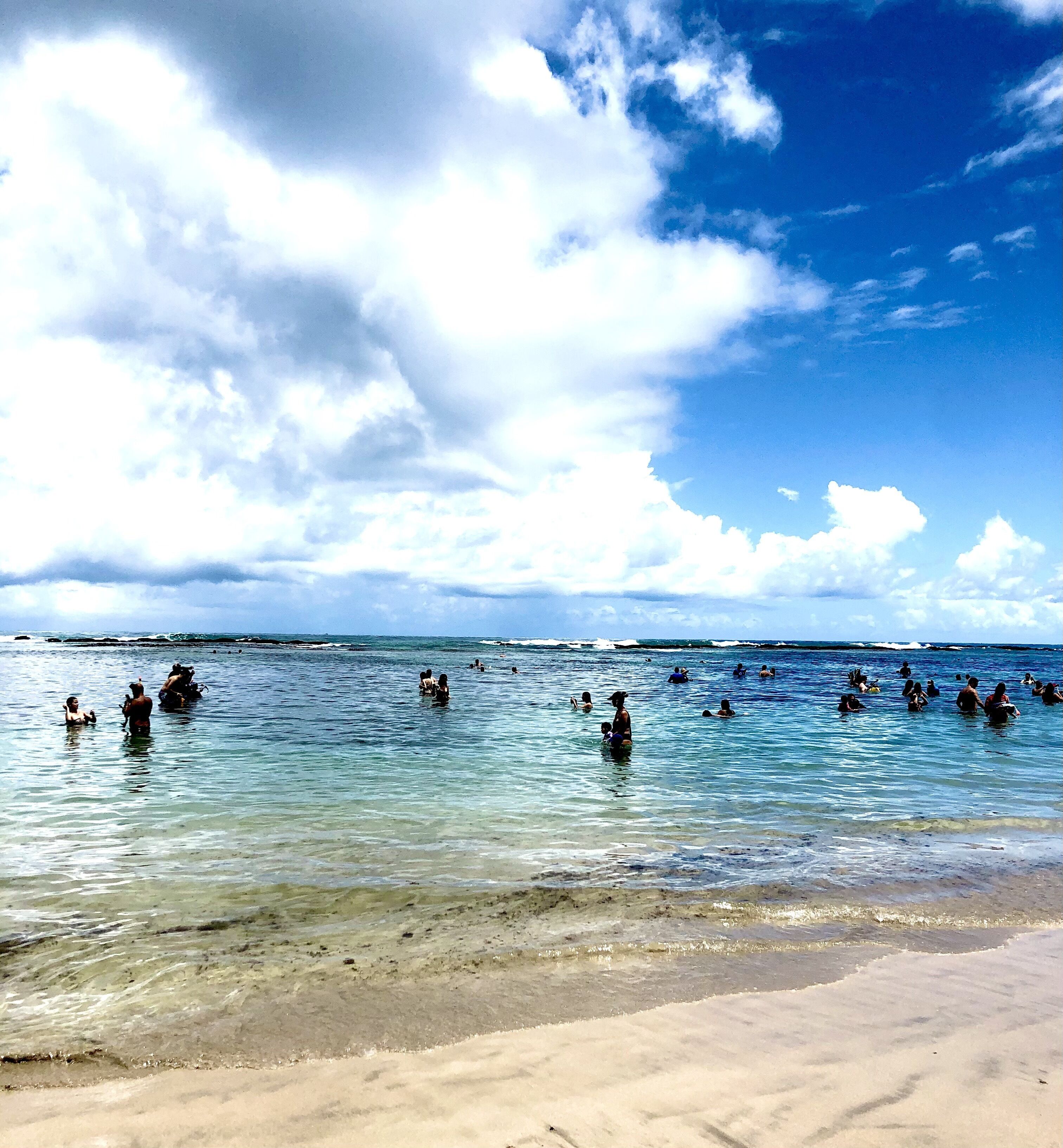 Une plage avec une eau claire et des gens qui se baignent.