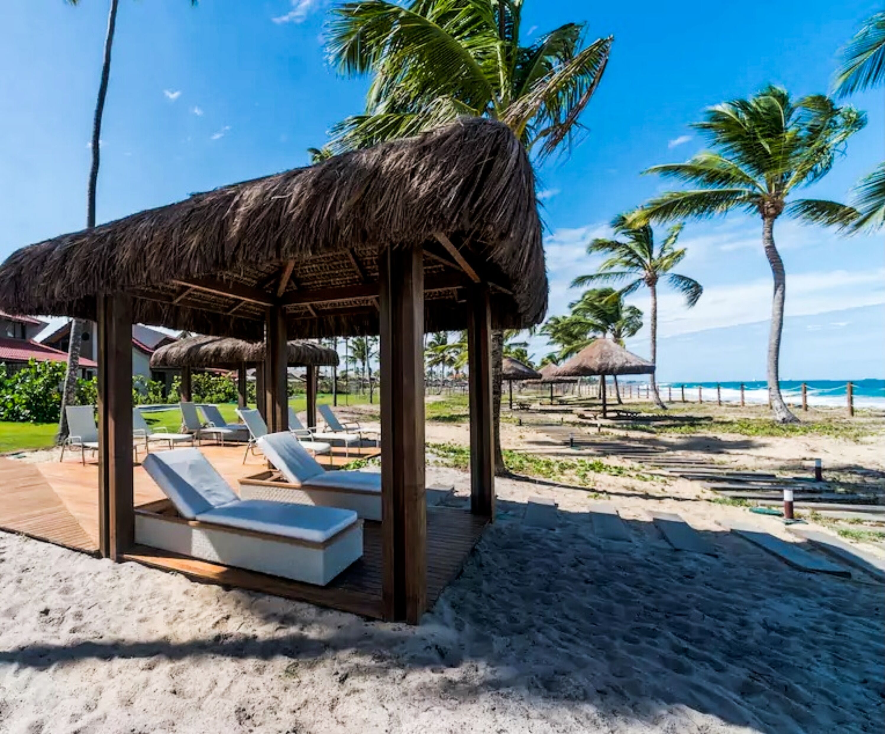 Na praia, areia branca, espreguiçadeiras, guarda-sóis 