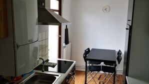 Una cocina compacta con estufa, lavamanos y mesa de comedor con sillas.