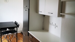 Una cocina compacta con una mesa y sillas, un refrigerador empotrado y un reloj fijado a la pared.