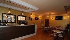 Zona de bar con mostrador, estantes llenos de botellas y un área de asientos con mesas y sillas.
